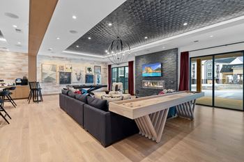 A modern living room with a large black sofa and a wooden coffee table.
